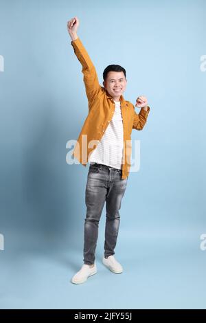 L'uomo asiatico LGBTQ con camicia gialla in piedi su sfondo blu. Foto Stock