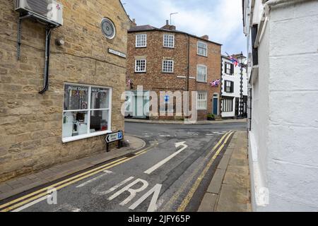 Strada inglese tipica a Knaresborough, Yorkshire con girare a sinistra freccia segnata sulla strada Foto Stock