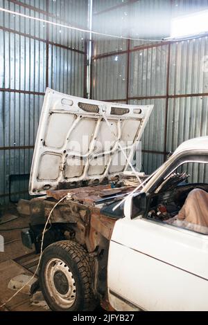 Disassemblato auto vecchia in garage vicino Foto Stock