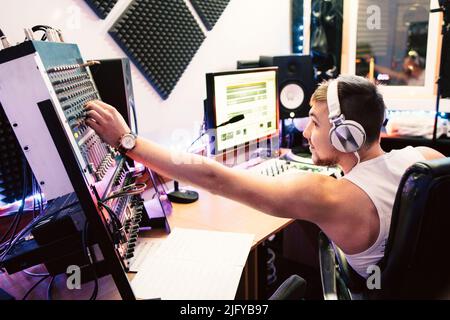 DJ regola le apparecchiature in studio di registrazione del suono Foto Stock