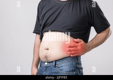 Dolore al corpo, dolore all'anca o effetto da problemi al fegato: L'uomo grasso usando la mano e premendo sulla posizione dell'anca. Studio girato su sfondo grigio. Foto Stock