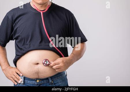 Medical Check up concetto: Grasso persone che tiene rosso medico stetoscopio per controllare la sua salute e il corpo. Studio girato su sfondo grigio Foto Stock