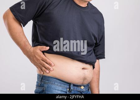 Dolore al corpo, dolore all'anca o effetto da problemi al fegato: L'uomo grasso usando la mano e premendo sulla posizione dell'anca. Studio girato su sfondo grigio. Foto Stock