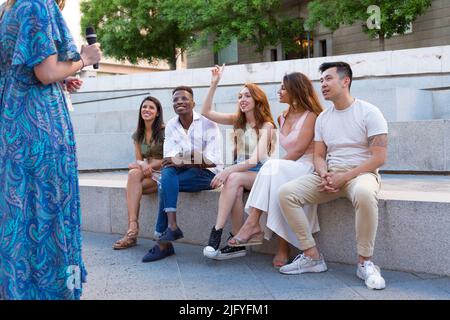 Gruppo di amici seduti su una panchina della città e una donna si offre come volontario.G Foto Stock