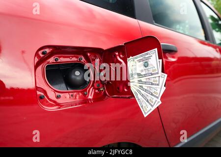 Primo piano di molte fatture cinquanta dollari ad un serbatoio di carburante aperto su un'automobile, simbolo per il prezzo di carburante crescente e costi di trasporto. Foto Stock