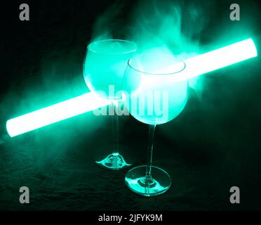 Cocktail Martini coperto di fumo a luce verde neon. Il tubo luminoso si illumina sullo sfondo. Foto Stock