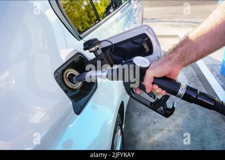 Mano di un uomo che riempie il serbatoio del carburante dell'auto in una stazione di servizio. Foto Stock