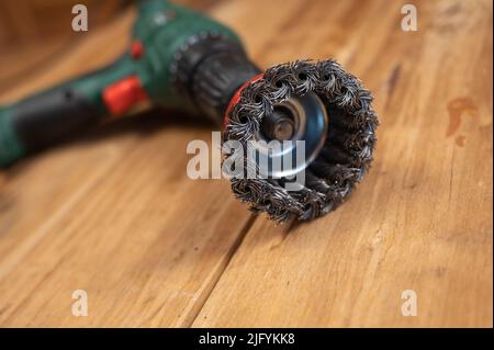 Spazzola metallica a tazza con nodo installata nella camma del mandrino di perforazione. Utensile per la lavorazione del legno, la levigatura, la rimozione della ruggine dalle varie superfici. All'interno della stanza Foto Stock