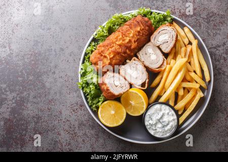 Bistecca di Karadjordjeva ripiena di kayak, impanata e fritta, servita con patatine fritte e salsa tartara da vicino in un piatto sul tavolo. Piano orizzontale Foto Stock