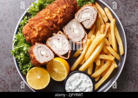 Karadjordjeva bistecca di vitello fritto o schnitzel di maiale servito con patate fritte con patatine fritte e salsa tartara da vicino in un piatto sul Foto Stock