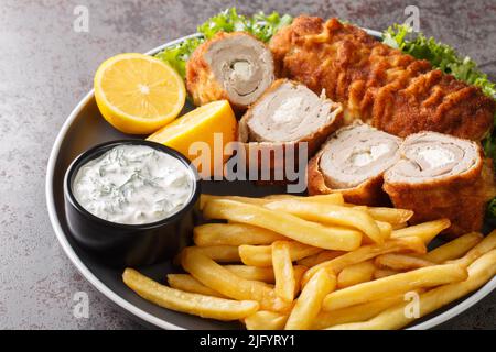 Karadjordjeva bistecca di vitello fritto o schnitzel di maiale servito con patate fritte con patatine fritte e salsa tartara da vicino in un piatto sul Foto Stock