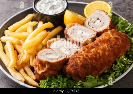 Filetto di carpetta arrotolato serbo Karageorge Schnitzel con patatine fritte e salsa tartara da vicino in un piatto sul tavolo. Orizzontale Foto Stock