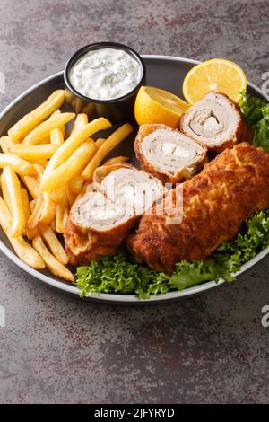 Caraffa Serba Karageorge Schnitzel servito con patatine fritte e salsa tartara in un piatto sul tavolo. Verticale Foto Stock