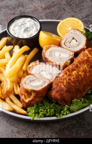 Karadjordjeva Schnitzel è un rotolo di maiale ripieno di Kaymak, impanato e fritto, servito con patatine fritte e salsa tartara primo piano in un piatto sul ta Foto Stock