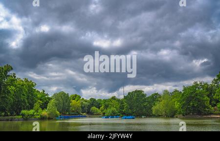 Vista di un piccolo laghetto in barca con una fila di pedalò parcheggiate, Crystal Palace Park, Londra, Regno Unito Foto Stock