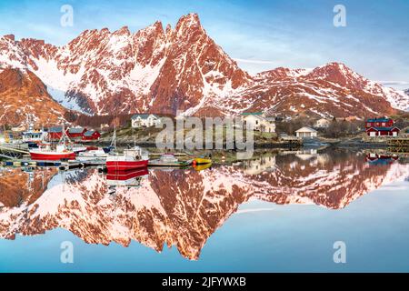 Barche da pesca e montagne innevate che si specchiano nel fiordo all'alba, Ballstad, Vestvagoy, Isole Lofoten, Norvegia, Scandinavia, Europa Foto Stock