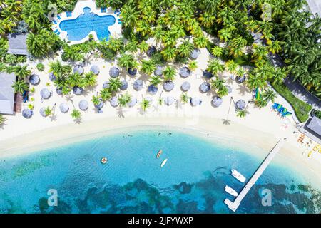 Canoe galleggianti nella laguna tropicale di resort di lusso con piscina sulla spiaggia frangiata di palme, Antigua, Indie Occidentali, Caraibi, America Centrale Foto Stock