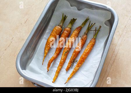 Carota intera giovane arrosto con verdure e sale marino in teglia da forno Foto Stock