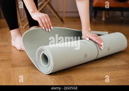 Fit ragazza che rotola fuori un tappeto yoga Foto Stock