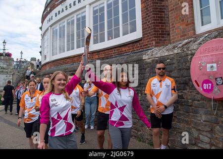 Windsor, Berkshire, Regno Unito. 6th luglio 2022. La Baton Carrier Jemma Wood (a sinistra) porta il batone lungo il Jennings Wharf sul fiume Tamigi a Windsor. Jemma è stato nominato da PwC per portare il testimone. Jemma ha fibrosi cistica e ha trascorso 740 giorni della sua vita in ospedale, 530 giorni dedicati ai nebulizzatori/fisiologico e prende 720 compresse al mese. Nonostante ciò, Jemma ha raggiunto l'adesione onoraria alla squadra di ginnastica dell'Università di Londra e ha raccolto oltre £300.000 persone per il Cystic Fibrosis Trust. Credit: Maureen McLean/Alamy Live News Foto Stock