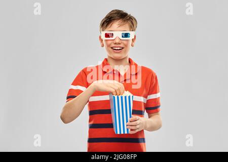 ragazzo sorridente in 3d occhiali da cinema che mangiano popcorn Foto Stock