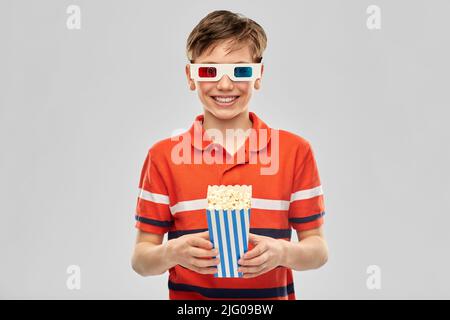 ragazzo sorridente in 3d occhiali da cinema che mangiano popcorn Foto Stock