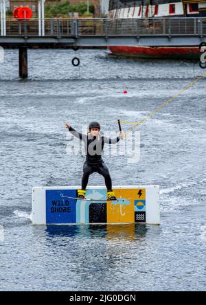 Dundee, Tayside, Scozia, Regno Unito. 6th luglio 2022. UK Meteo: Una giornata nuvolosa con venti freddi ad ovest, temperature che raggiungono i 18°C nella Scozia nord-orientale. I wakeboarder del Wild Shore possono praticare sport acquatici e godersi una giornata di wakeboarding su un treno al West Victoria Dock di Dundee's City Quay. Credit: Dundee Photographics/Alamy Live News Foto Stock