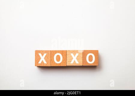 Il carattere di xoxo. Abbracci e baci. Espressione di affetto. Scritto su quattro blocchi di legno. Lettere bianche. Sfondo bianco. Foto Stock