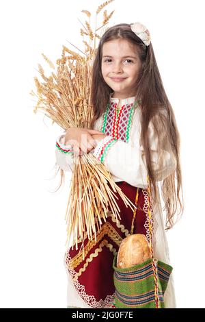 Donna bulgara o giovane ragazza in abito tradizionale folclore tiene in mano il grano dorato e pane fatto in casa appena sfornato in una borsa Foto Stock