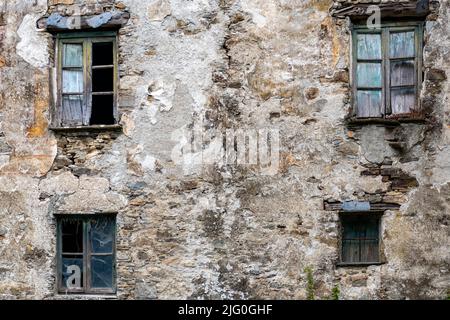 La facciata di un vecchio edificio abbandonato con finestre rotte Foto Stock