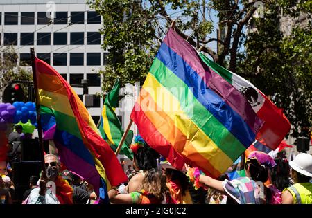 Persone che partecipano alla sfilata di orgoglio in città con enormi bandiere di orgoglio arcobaleno. Foto scattata a San Francisco, Stati Uniti d'America il 26 2022 giugno Foto Stock