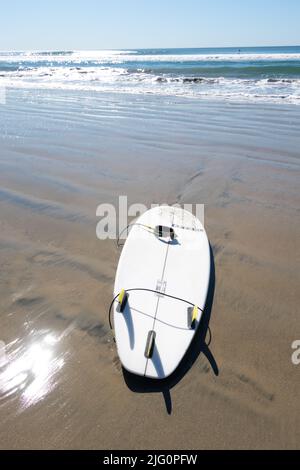 Lone Surfboard su sabbia bagnata con mare sullo sfondo Huntington Beach California meridionale USA Foto Stock