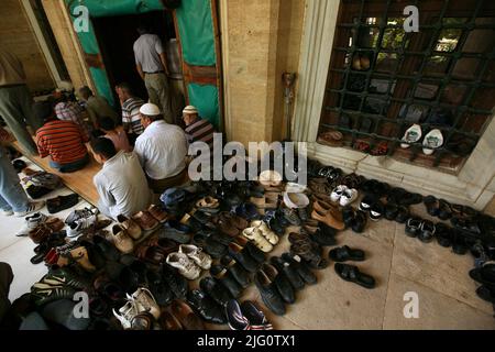 Kırkpınar (olio turco Wrestling). Le scarpe lasciarono accanto all'ingresso durante la preghiera del venerdì (Jumu'ah) nella moschea di Selimiye a Edirne, Turchia. La preghiera congregazionale nella moschea di Selimiye segna l'inizio del torneo annuale di Kırkpınar 648th, il 2 luglio 2009. Il torneo annuale di lotta all'olio turco inizia tradizionalmente con la preghiera del venerdì nella moschea di Selimiye progettata dall'architetto imperiale ottomano Mimar Sinan e costruita tra il 1568 e il 1575. Alcune persone pregano all'esterno perché la moschea è già piena. Foto Stock