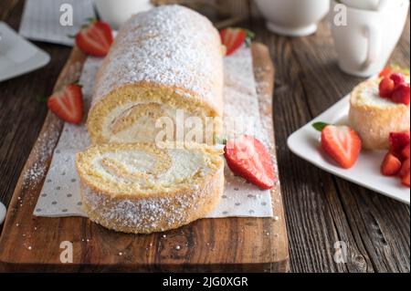 Rotolo di biscotti o rotolo svizzero con panna montata e fragole Foto Stock
