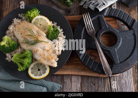 Cena fitness con pesce, riso integrale e broccoli su un piatto Foto Stock