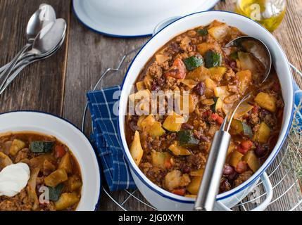 Stufato di manzo macinato con cavolo, verdure e fagioli di rene. Servito in una pentola da cucina rustica su sfondo di tavolo di legno Foto Stock