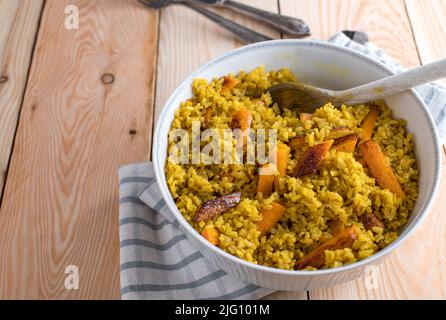 Contorno sano con riso marrone, curcuma e carote arrostite in una ciotola Foto Stock