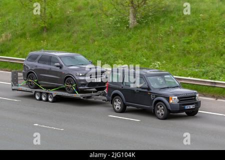 2006 Black Land Rover Discovery TDV6 190 2720cc Diesel SUV rimorchio per auto che trasporta 2019 Dodge (USA) SRT 6400cc benzina SUV; guida sull'autostrada M6, Manchester, Regno Unito Foto Stock