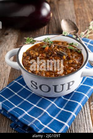 Stufato di lenticchie vegane o vegetariane con verdure e melanzane su tavola di legno. Vista laterale con spazio di copia Foto Stock