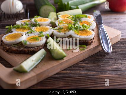 Panino intero con fette di uova bollite. Condito con pepe, sale e erba cipollina Foto Stock