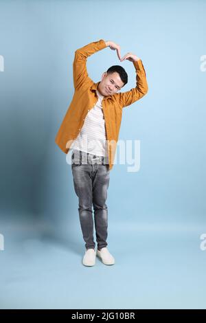 L'uomo asiatico LGBTQ con camicia gialla in piedi su sfondo blu. Foto Stock