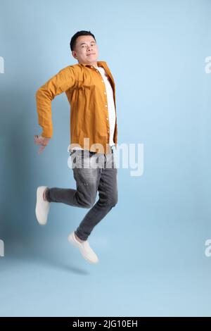 L'uomo asiatico LGBTQ con camicia gialla in piedi su sfondo blu. Foto Stock