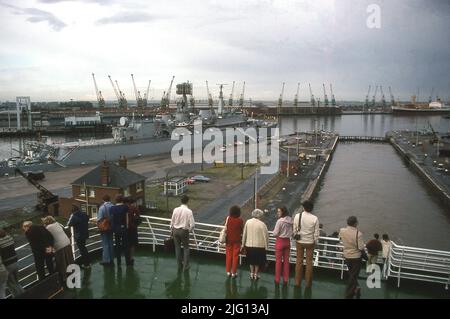 1981, storico, persone in piedi guardando su King George Dock, Hull, Inghilterra, Regno Unito, con una nave Royal Navy ormeggiata. Il porto fu aperto da re Giorgio V il 1914 giugno. Foto Stock