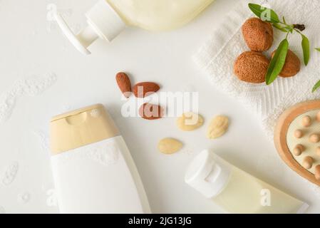 Prodotti per l'igiene personale con estratto di mandorle su tavola bianca con frutta e prodotti da bagno. Vista dall'alto. Composizione orizzontale. Foto Stock