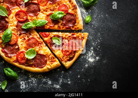 Pizza italiana tradizionale con salumi, pomodori e basilico. Foto Stock