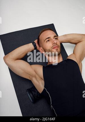 Man Foam Rolling. L'atleta si allunga utilizzando un rullo in schiuma. Foto Stock