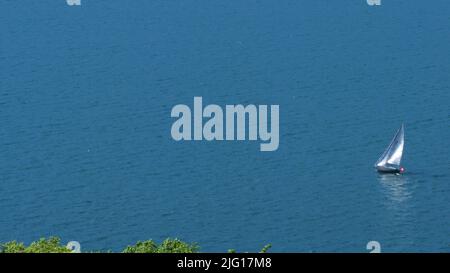 Una foto di sfondo con una barca a vela su un lago Foto Stock