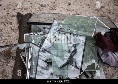 Mucchi di vetro rotto dalle finestre dagli edifici di appartamento sono stati abbattuti dall'onda d'esplosione come risultato dell'aria missilistica di crociera di Kalibr Foto Stock