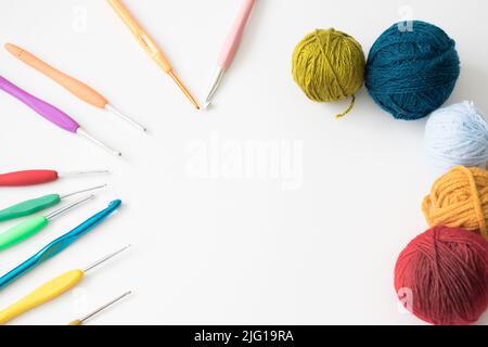 Concetto di idea di crochet, crochet e sfere di lana sono disposti in un cerchio. Aghi colorati e fili. Nessuna gente, nessuno. Spazio per la copia, spazio per il testo. Foto Stock