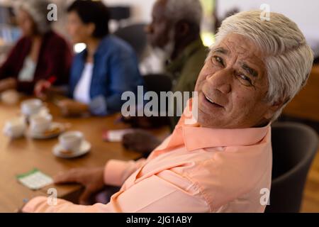 Ritratto di sorridente biraciale anziano che gioca bingo con amici multirazziali in casa di cura Foto Stock